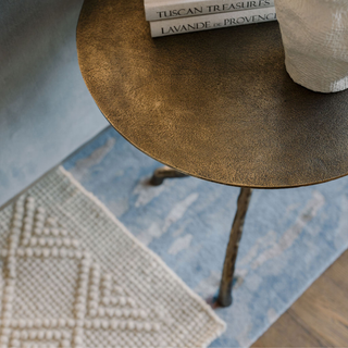 Top view of the CG Hunter Handcrafted Antique Brass Aluminum Accent Table adorned with books and a decorative vase, highlighting its artisanal craftsmanship and stylish presence.