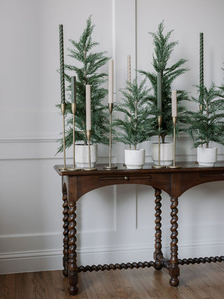 Handcrafted Antique Brass Candlesticks by CG Hunter, gracefully positioned on a vintage wooden table, adorned with lush greenery for an upscale decor aesthetic.