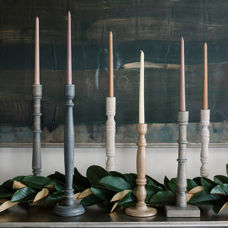 Beautifully arranged tapered candle holders in different shades by CG Hunter, including dark grey wood, creating an inviting and luxurious atmosphere.
