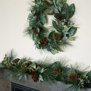 Elegant arrangement featuring a 28" magnolia, eucalyptus, pinecone, and needle pine wreath by CG Hunter, paired with a decorative garland, enhancing festive home decor.
