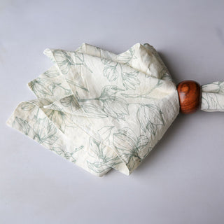 Artfully folded CG Hunter Grey and Green Lilies Napkin, adorned with delicate floral patterns, ideal for adding a sophisticated touch to any table setting.