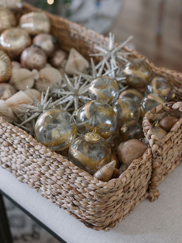 a beautiful set of Hand Blown Glass Gold Etched Ornament in a woven basket awaiting to be placed on the tree