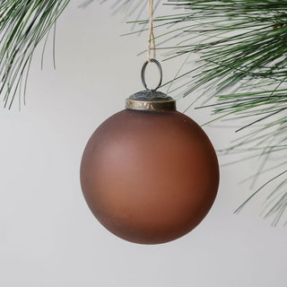 Elegant 3" Frosted Cinnamon Glass Ornament by CG Hunter, showcasing a sophisticated frosted finish hanging gracefully from a pine branch.