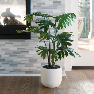 Stylish CG Hunter 3' Faux Potted Philodendron displayed in a modern living room, adding a touch of luxury and greenery beside a fireplace.