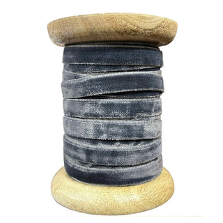 CG Hunter Narrow Hand Dyed Velvet Ribbon in a soft, muted grey, artistically wound on a wooden spool, highlighting its artisanal quality and luxurious feel, ideal for upscale decor and crafts.