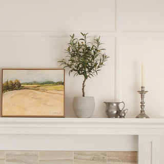 Luxurious living room featuring a lifelike Artificial Olive Topiary Tree with Mediterranean Pot by CG Hunter, elegantly placed on a mantle alongside artwork and stylish decor.