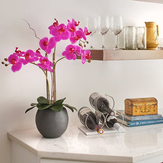 Elegant display of the Artificial Pink Double Stem Orchid by CG Hunter in a contemporary gray pot, complementing a stylish kitchen setting with wine bottles.