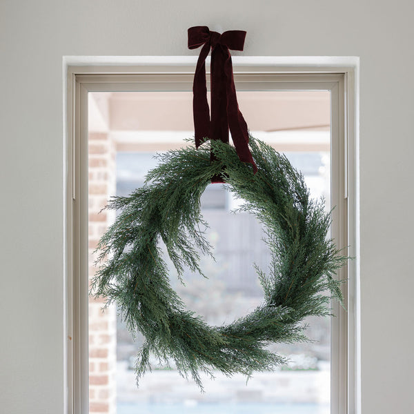 Close up of 30" Lifelike Cedar Wreath on window with wide ribbon