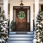 A luxurious winter wreath adorns a beautiful front door, creating an inviting entrance for the New Year and beyond. The snowy steps and evergreen trees enhance the serene winter aesthetic.
