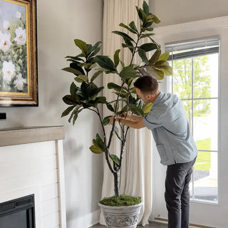 Designer Chase Hill styling the base of a faux magnolia tree with moss to conceal the nursery pot for a finished, designer look.