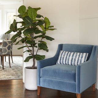 Elegant corner featuring a 7' artificial Fiddle Leaf Fig tree next to a luxurious blue chair, showcasing CG Hunter's Trees collection of realistic faux trees that elevate home decor.