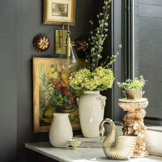 Elegant home decor setting featuring a stylish black console table adorned with a lush greenery centerpiece, candles, and a decorative vase. Perfect inspiration for gifts for the decor enthusiast, showcasing sophisticated decor enthusiast gifts.