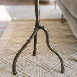 Close-up detail of the sturdy base of the CG Hunter Handcrafted Antique Brass Aluminum Accent Table, showcasing its artisanal craftsmanship and intricate finish.