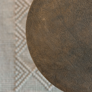 Close-up view of the textured surface of the CG Hunter Handcrafted Antique Brass Aluminum Accent Table, showcasing its rich finish and luxurious design.