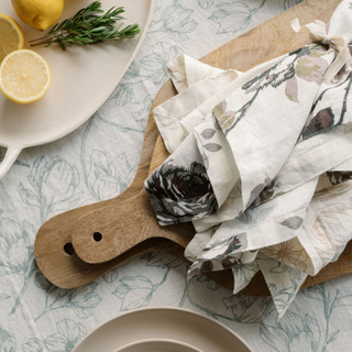 Charming arrangement of CG Hunter Eggplant and Grey Roses Tablecloth and Napkins atop a rustic wooden table, complemented by fresh lemons and herbs, ideal for luxurious gatherings.