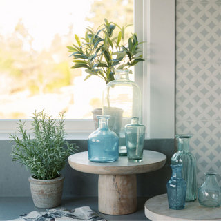 12" Rosemary & 16" Olive Topiary Set by CG Hunter styled in a bright setting with glass vases, showcasing a realistic faux topiary set, perfect for adding a spring faux feel to your tabletop plant collection.