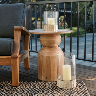 CG Hunter Handcrafted Clear Glass and Rattan Candleholders enhancing a stylish outdoor seating area, providing soft illumination alongside rustic wooden decor.