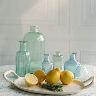 Sophisticated display of CG Hunter's Assorted Blue and Green Glass Bud Vases surrounded by vibrant lemons and fresh herbs on a decorative tray, enhancing the luxurious ambiance.