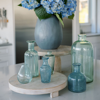 Chic display of CG Hunter handcrafted blue and green glass bud vases artfully arranged with vibrant hydrangeas, perfect for sophisticated interior styling.