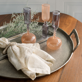 Elegant table setting featuring CG Hunter Handcrafted Linen Blush Lilies Napkins set elegantly alongside glass candle holders on a rustic tray, enhancing any sophisticated dining experience.