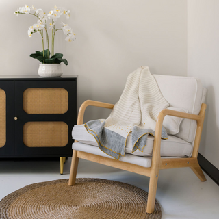 CG Hunter Natural and Brown Round Braided Jute Rug showcased elegantly under a stylish armchair with a cozy throw. This eco-friendly rug elevates contemporary decor with its artisanal charm.