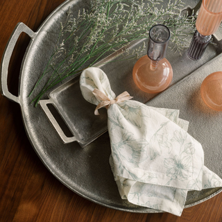 Elegant arrangement featuring CG Hunter Grey and Green Lilies Tablecloth and Napkins, complemented by delicate floral accents on a polished silver tray.