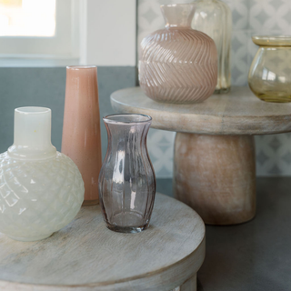 Stylish display of CG Hunter's assorted yellow and peach glass bud vases arranged on a wooden pedestal, perfect for enhancing modern and boho interiors.