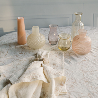 An artistic arrangement of CG Hunter Handcrafted Assorted Yellow and Peach Glass Bud Vases on a table, highlighting the variety of shapes and botanical-inspired colors.