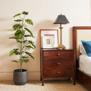 Luxurious 5' Artificial Monstera Tree by CG Hunter featured beside a classic wooden nightstand, bringing organic elegance to a stylish bedroom.