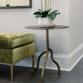Stylish CG Hunter Handcrafted Antique Brass Aluminum Accent Table placed next to a plush green sofa, adorned with a chic planter for a luxurious home decor look.