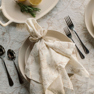 Elegant table setting featuring CG Hunter Blush Lilies Tablecloth and Napkins, showcasing beautiful floral patterns on premium linen with soft blush tones, ideal for luxury dining experiences.