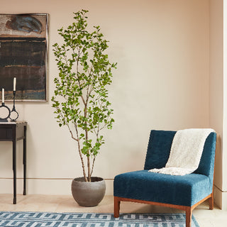 Luxurious interior featuring CG Hunter's 7' Artificial Heart Ficus Tree in a stylish pot, complemented by elegant decor and a plush chair.