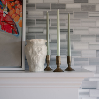 Elegant display of CG Hunter's 3.5" Iron Candleholders in Antique Brass with mint green taper candles on a modern mantel against a chic grey tile backdrop.