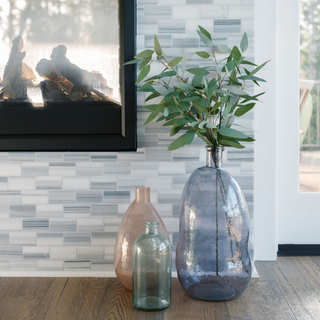 Contemporary interior scene featuring multiple CG Hunter Handmade Hammered Glass Vases in Peach and blue, elegantly styled around a fireplace, enhancing the luxurious ambiance.