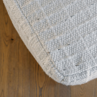 Close-up view of the sumptuous texture of the CG Hunter Square Striped Woven Ottoman Pouf, showcasing its luxurious woven design on a warm wooden surface.