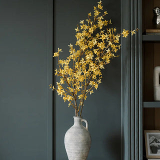 White vase with yellow flowers against a dark wall