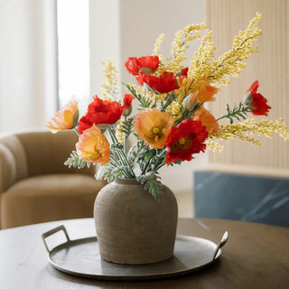 Vase with red and yellow flowers on a table in a room setting