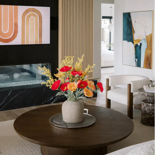 Decorative flowers in a vase on a coffee table in a living room setting.