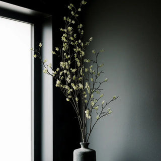 Vase with dried branches against a dark wall