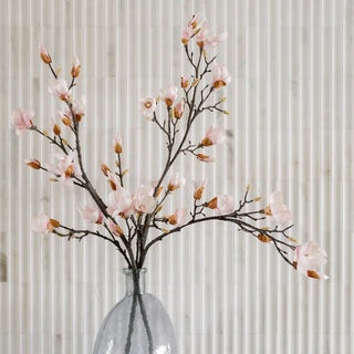 Decorative floral arrangement with pink flowers in a clear glass vase against a neutral background