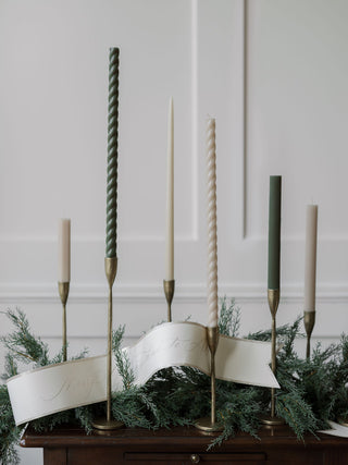 Handcrafted Antique Brass Candlesticks by CG Hunter, showcased with an array of elegant candles and decorative greenery, radiating sophistication and charm.