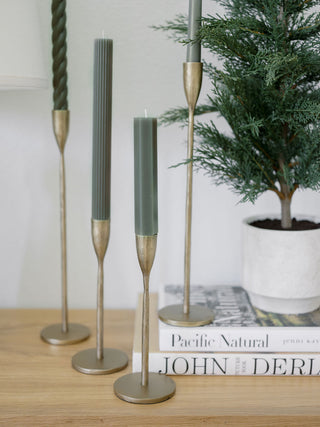 Chic display of handcrafted antique brass candlesticks from CG Hunter, featuring green candles and curated home accents, perfect for a luxury interior.