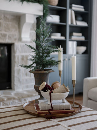 Charming tabletop arrangement featuring handcrafted antique brass candlesticks by CG Hunter, complemented by festive decor and candles in a cozy living space.