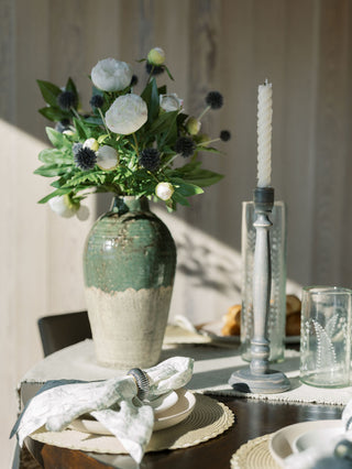 Decorative table setting with a vase of flowers, candles, and place settings.
