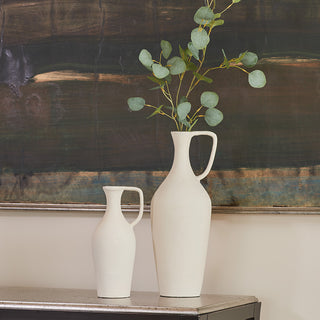Close up of matching creme pitchers with green branch