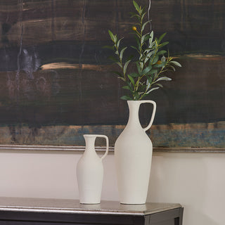 Close up of matching creme pitchers with olive branch