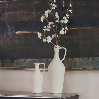 Close up of matching creme pitchers with white flower branch