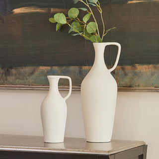 Close up of matching creme pitchers with green branch