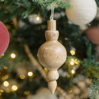 Handcrafted 5" Wooden Finial Christmas Ornament artfully suspended among holiday decorations by CG Hunter, highlighting the natural beauty of mango wood.