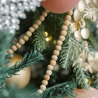 Luxurious 8' Natural Wood Bead Garland by CG Hunter, beautifully draped among festive greenery, adding a warm, handcrafted touch to holiday decor.